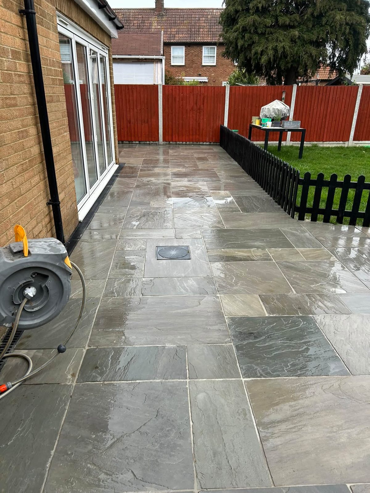 After: the same patio cleaned, revealing clean grey and buff sandstone